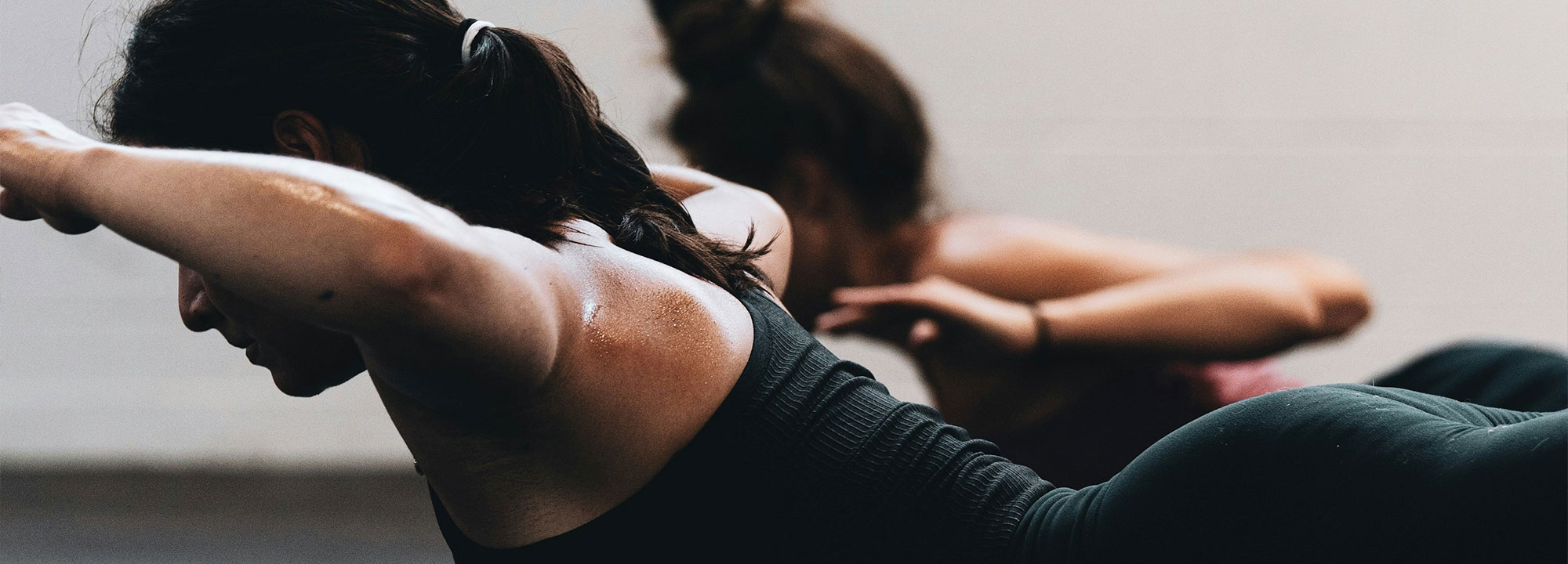 A person lying on their front on a yoga mat with their arms raised at their sides