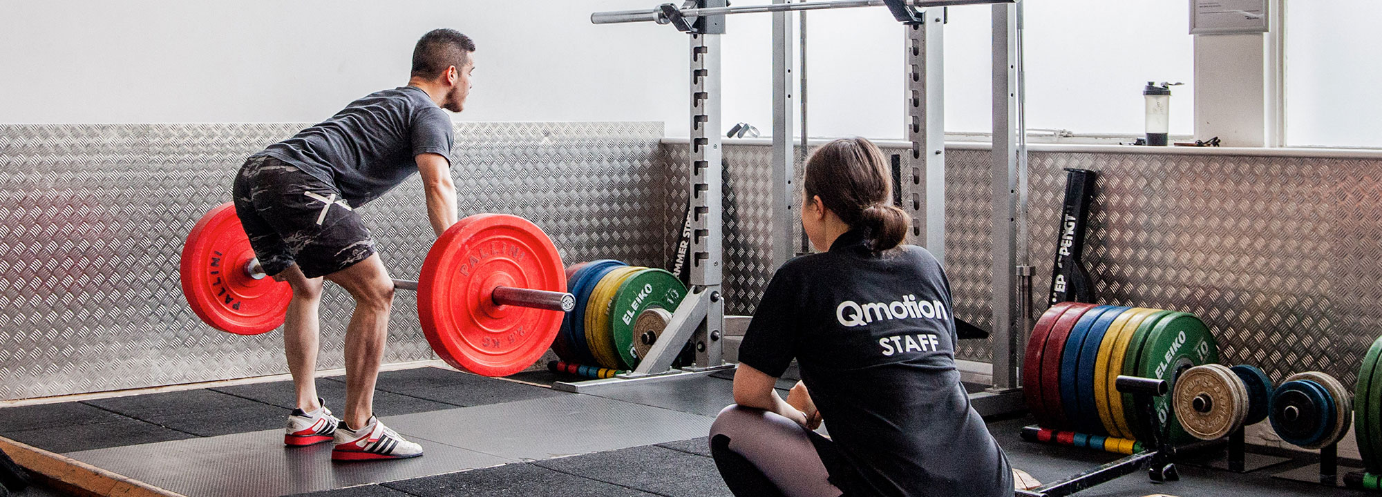 A student performing a lift with the help of QMOTION staff