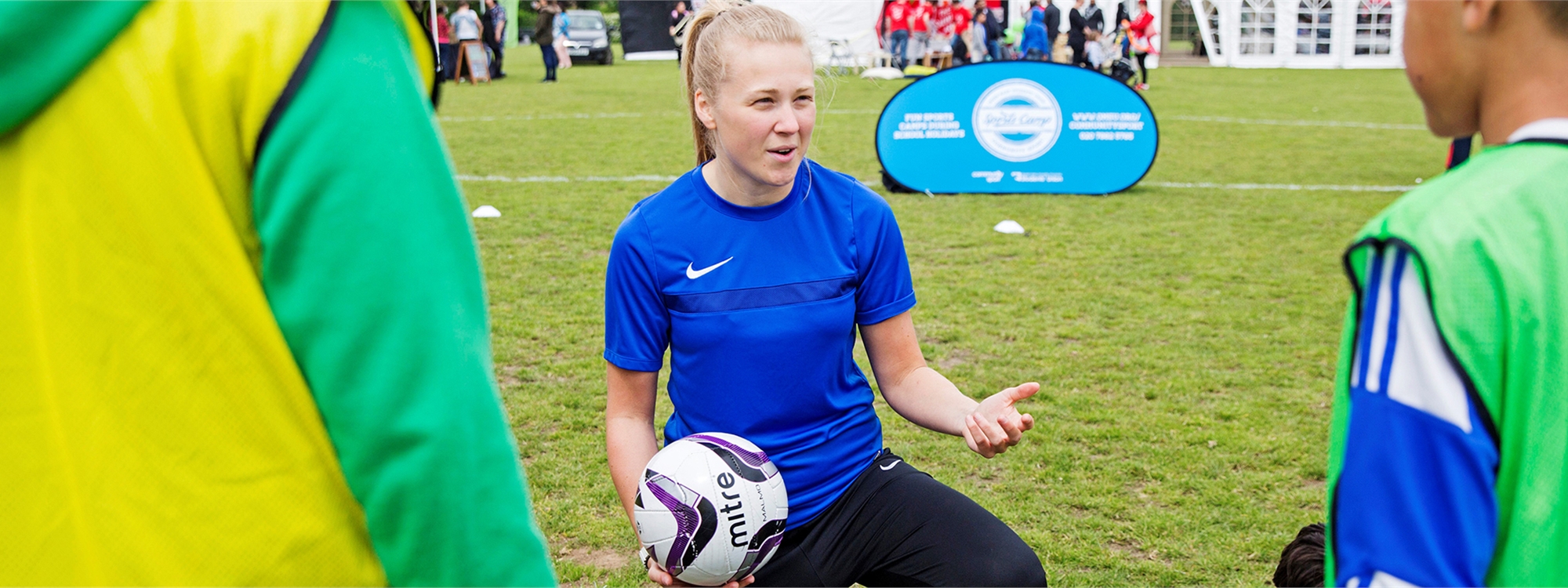 A student crouching down with a football talking to other students