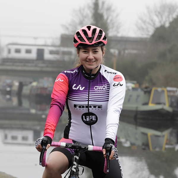 Connie Hayes smiling and riding a bike in front of a river